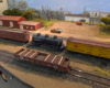 An HO scale reefer, three dome tank car, and boxcar behind a gondola with rebar load
