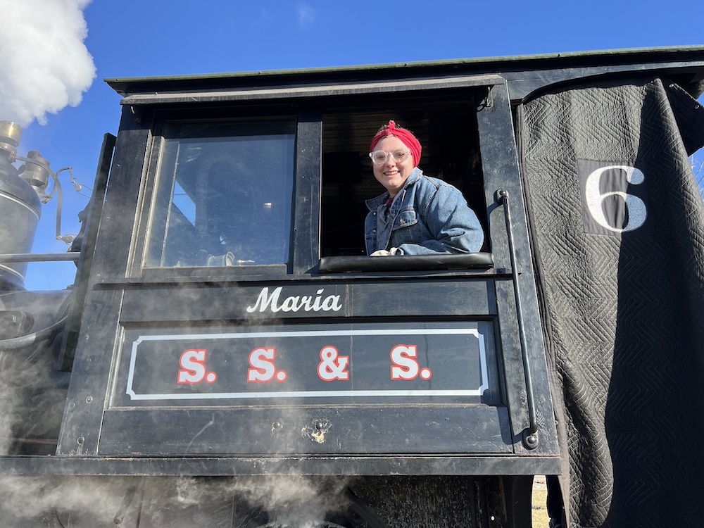 Young individual sitting in the cab of a steam locomotive