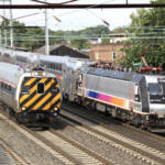Passenger train led by cab car passes stopped commuter train with locomotive in push mode.