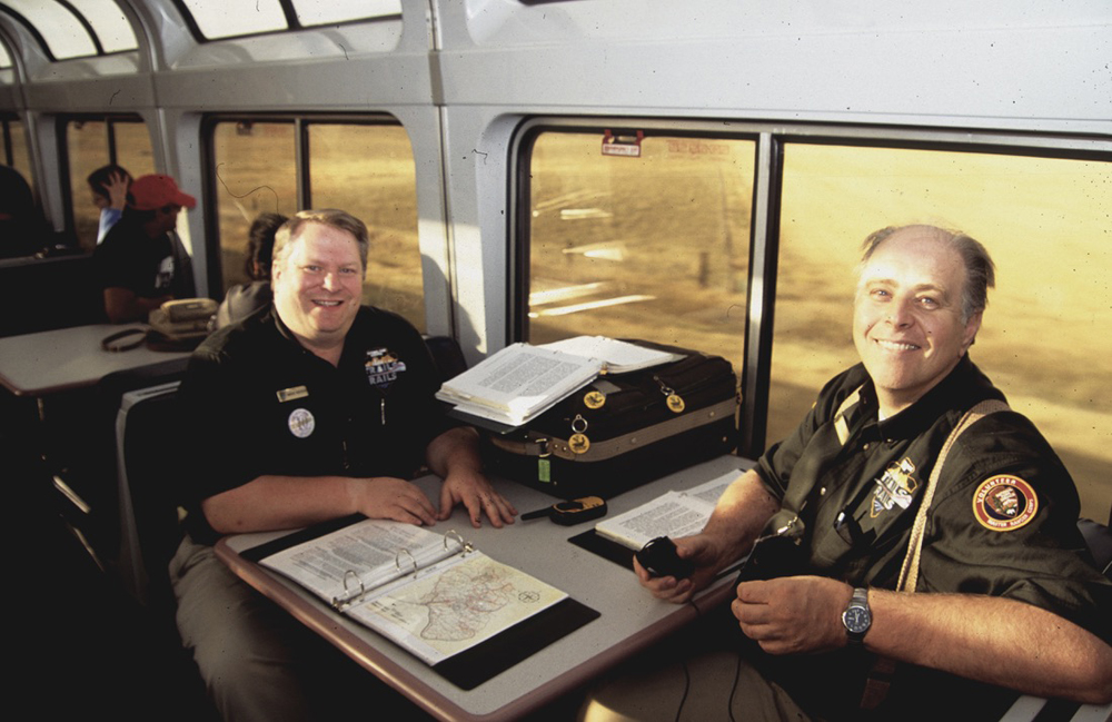 Two men in National Park Service uniforms sitting at table in passenger car