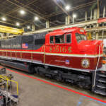 Red, maroon, and gray locomotive in shop building