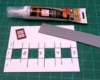 piece of model siding, adhesive, window on cutting board

