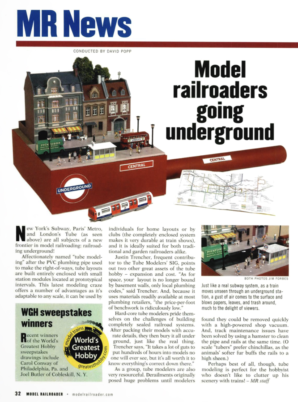 Page from a printed magazine featuring a photo of a model of a city street, plus a small colorful map, and red, white, and gray model train car, and black and blue text on white paper.