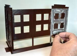 Piece of stiff cardboard packaging scrapes joint compound from brick building walls