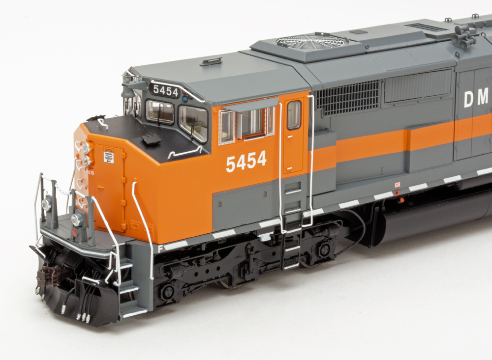 Color photo showing front end of HO scale diesel painted gray and orange on white background.