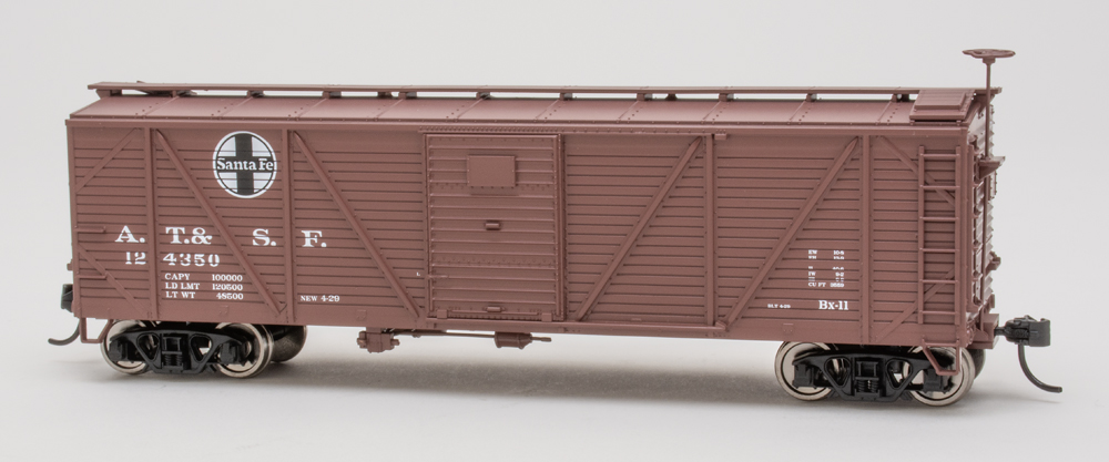 Color photo of HO scale boxcar painted brown with black and white graphics on white background.