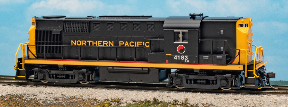Color photo of HO scale diesel locomotive painted black, yellow, and red on scenicked base.