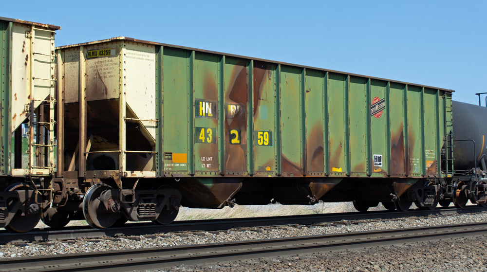 Color photo of weathered hopper car painted green and yellow.