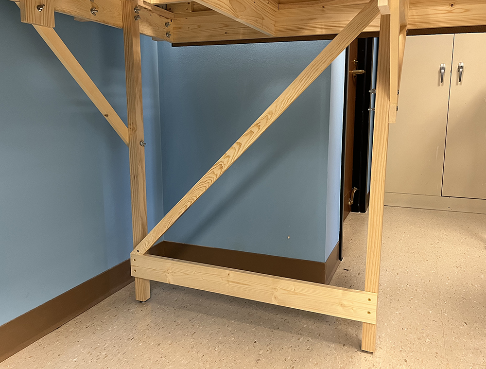 bare wood furniture legs with a narrow wood brace attached at a 45-degree angle between the two legs from top to bottom.