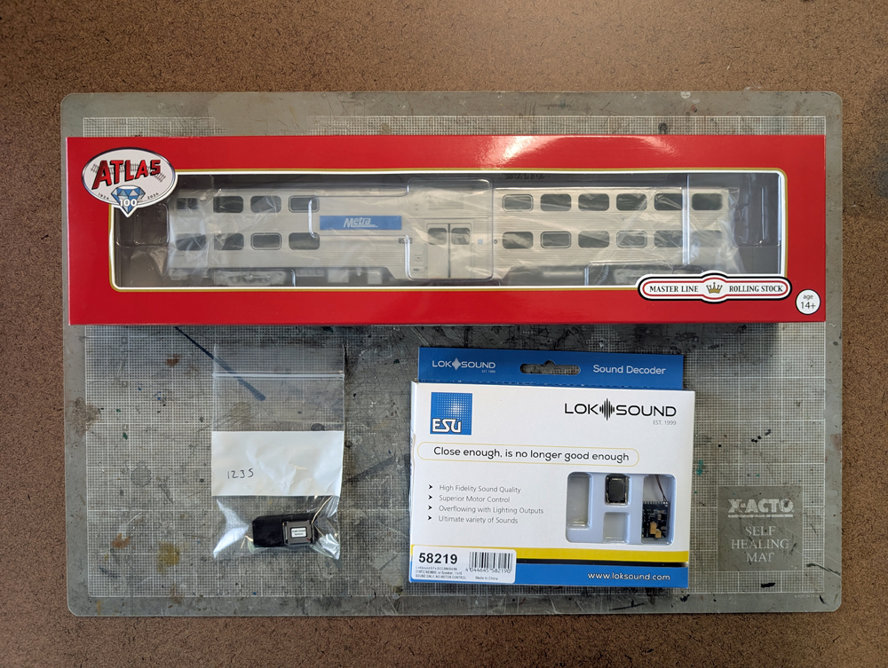 An HO scale passenger car above a speaker and decoder