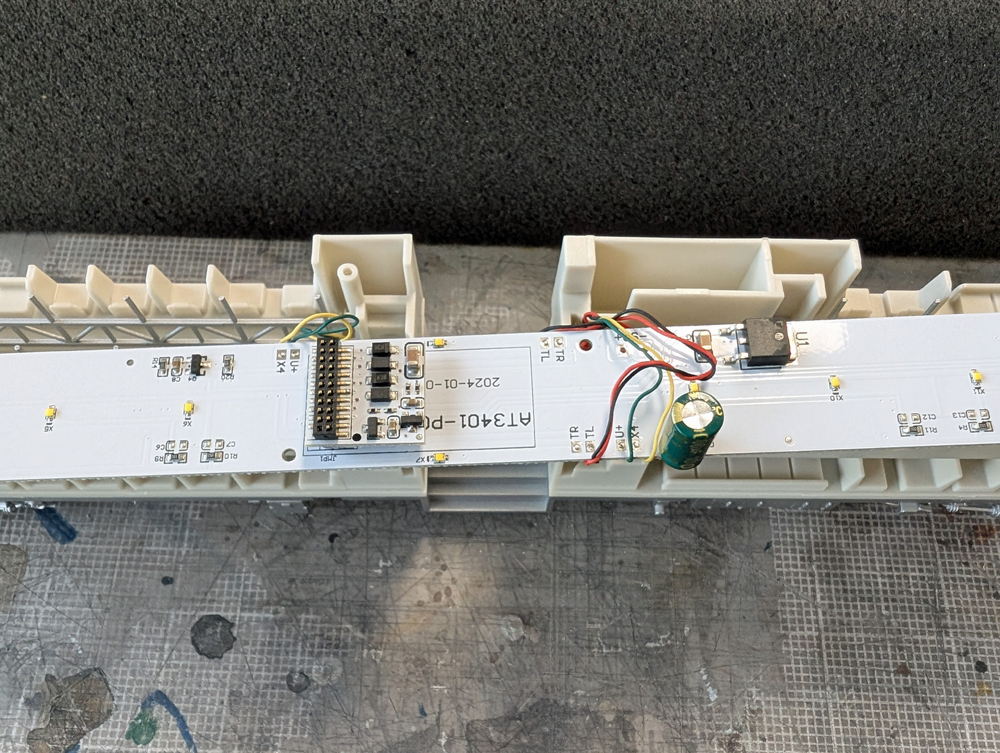 The underside of an HO scale passenger car light board showing a DCC decoder dummy plug.