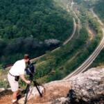 Cameraman filming steam train from cliff