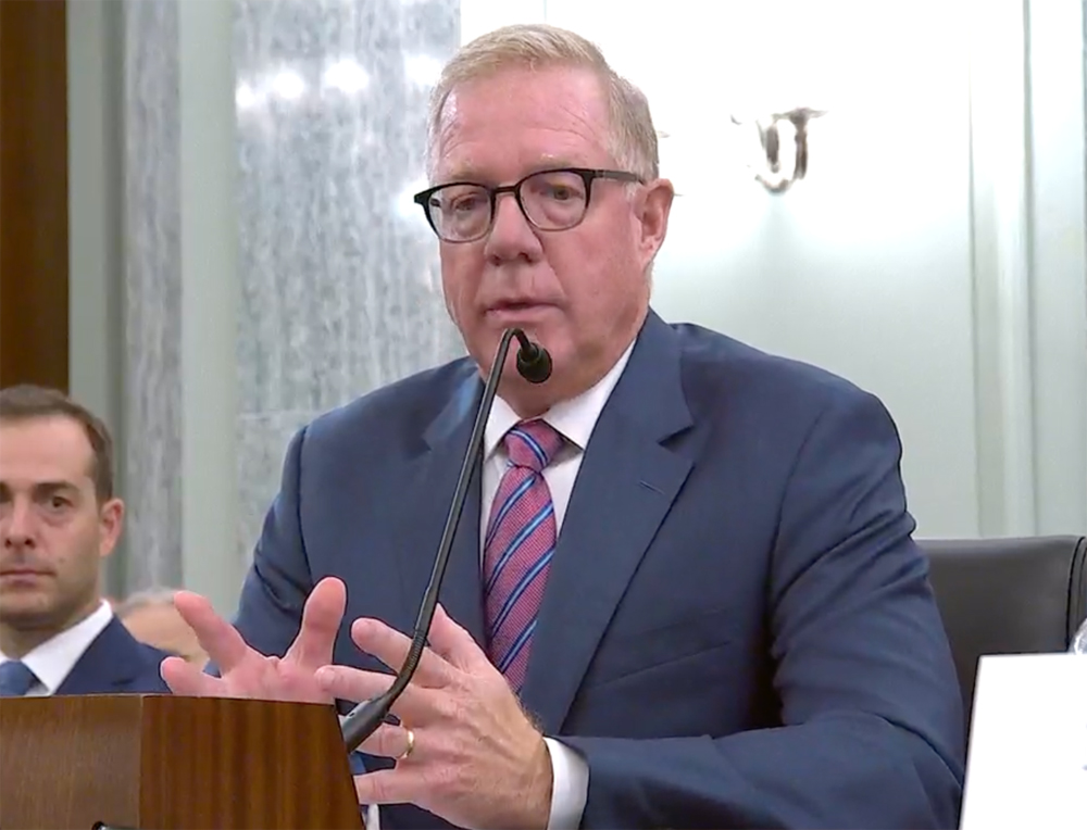 Man at microphone gesturing as he speaks