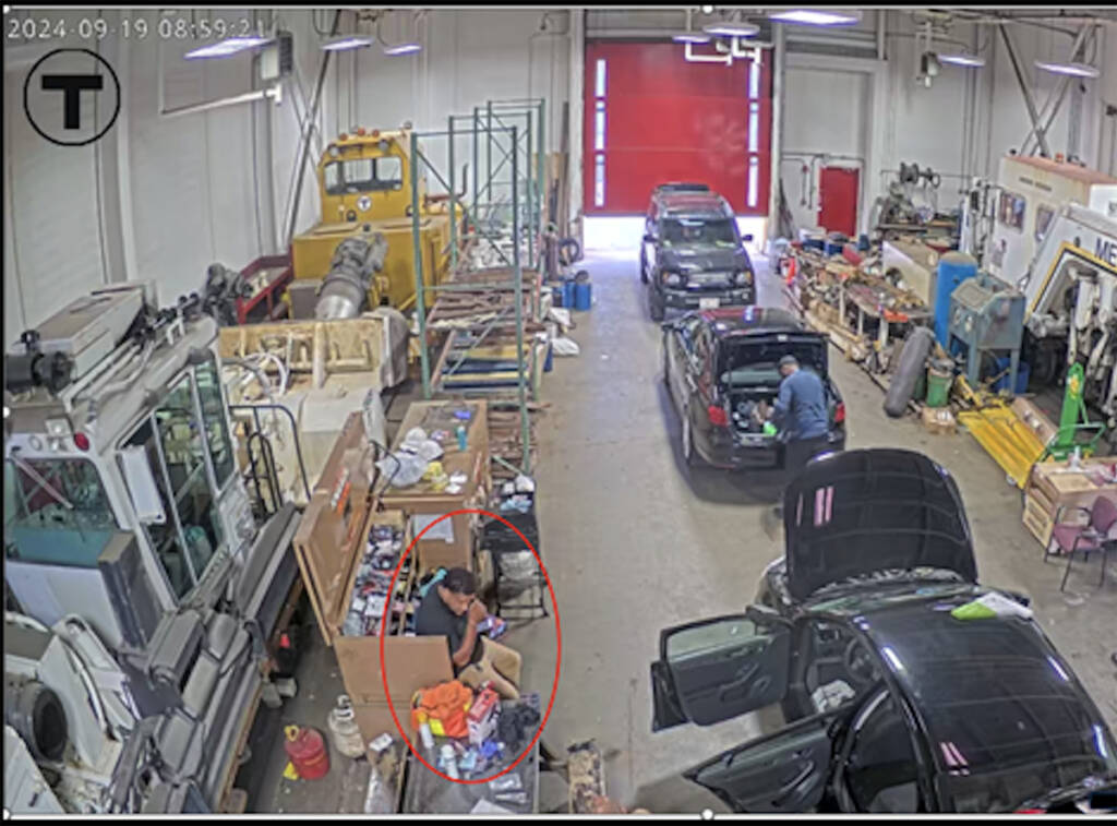 Interior view of garage with several people and vehicles