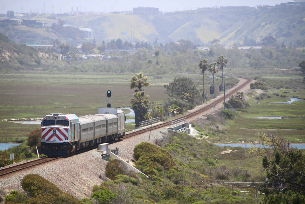 Short passenger train on straight track across open wetlands