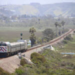 Short passenger train on straight track across open wetlands
