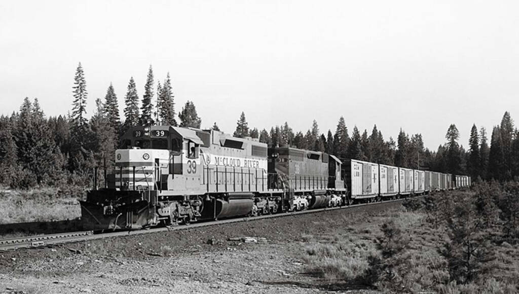 A black and white photograph of a diesel locomotive leading a freight train