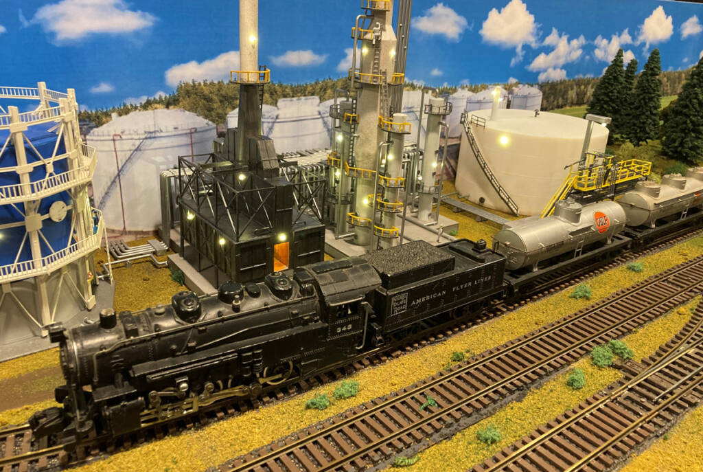 A black steam toy locomotive on a toy train layout
