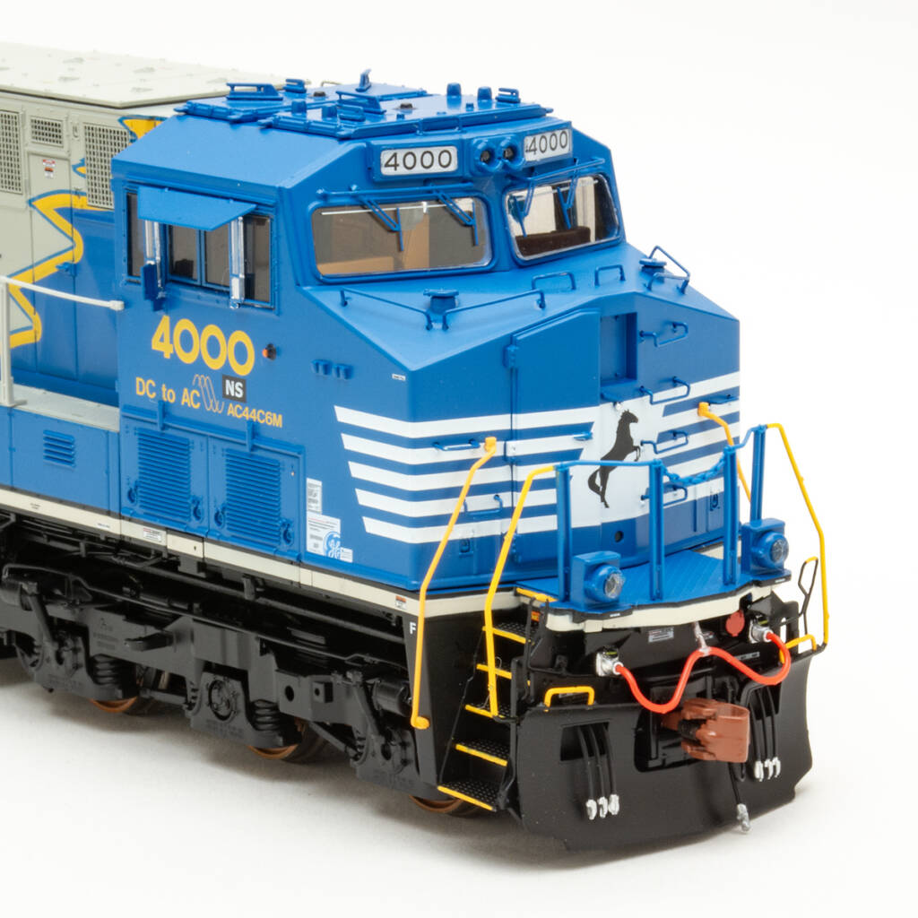 Photo of HO scale diesel painted blue, white, yellow, gray, and black on white background.