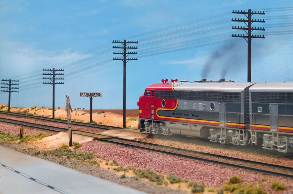 A silver and red model locomotive in a desert setting model railroad