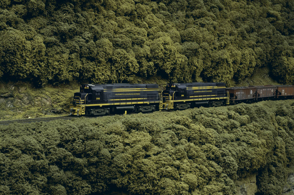 A coal train proceeds up an incline on a model railroad layout