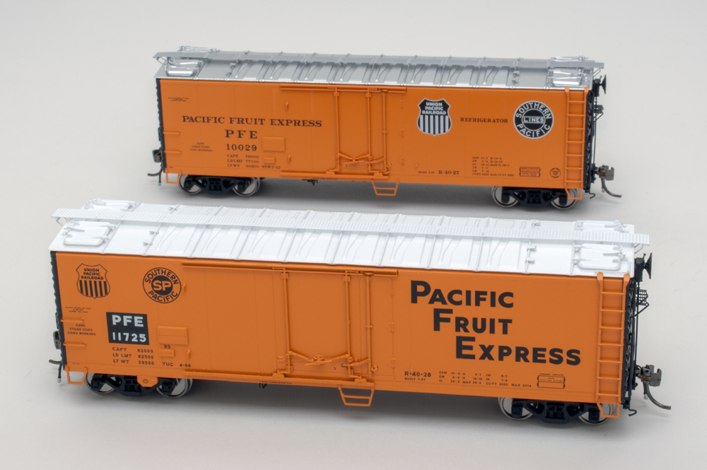 Color photo of two HO scale freight cars painted orange and black on white background