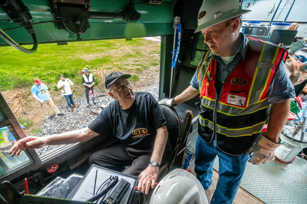 Older gentleman sits in cab of steam locomotive