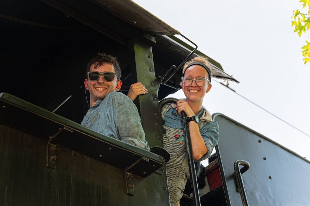 Young individuals in the cab of a steam locomotive