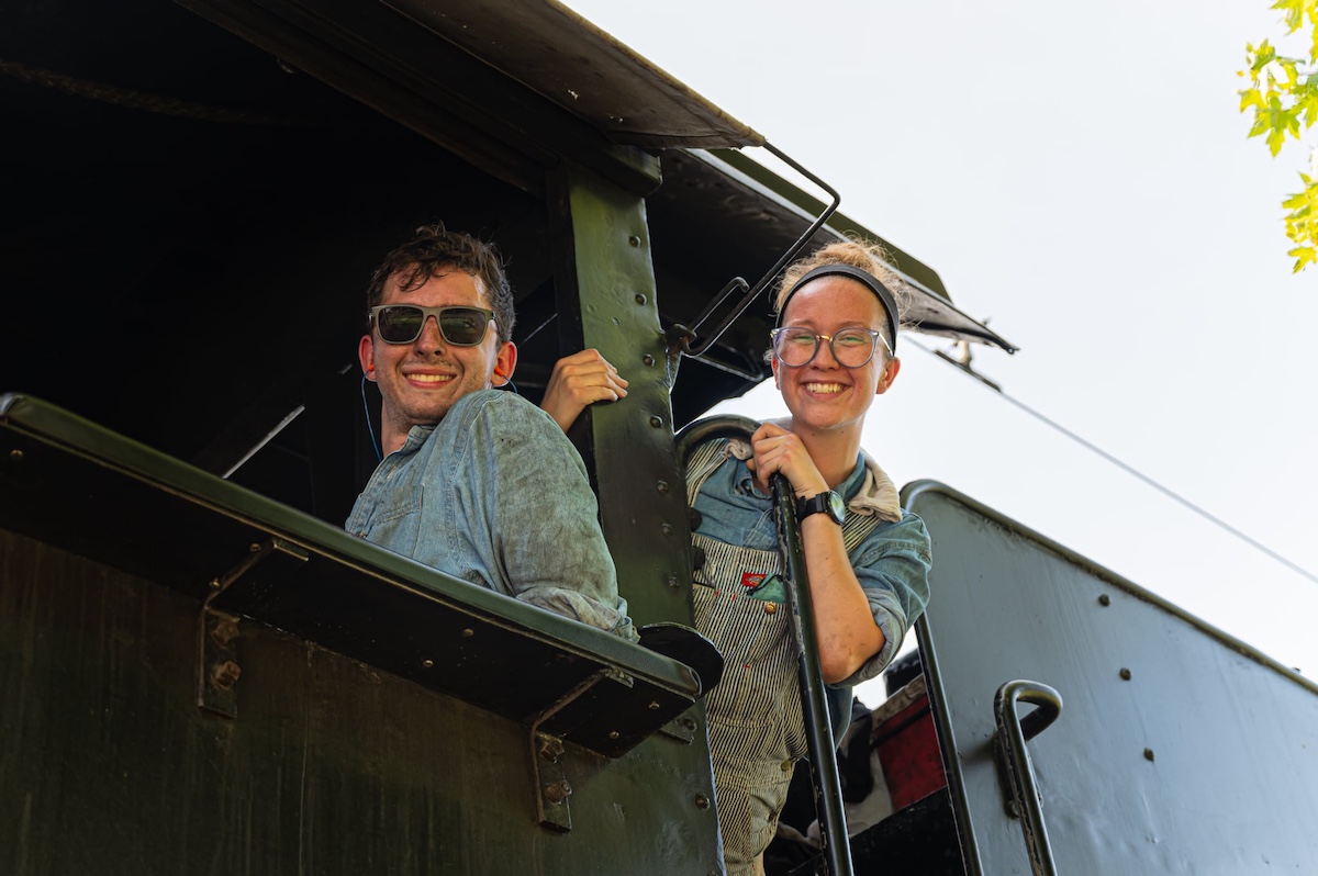 Young individuals in the cab of a steam locomotive