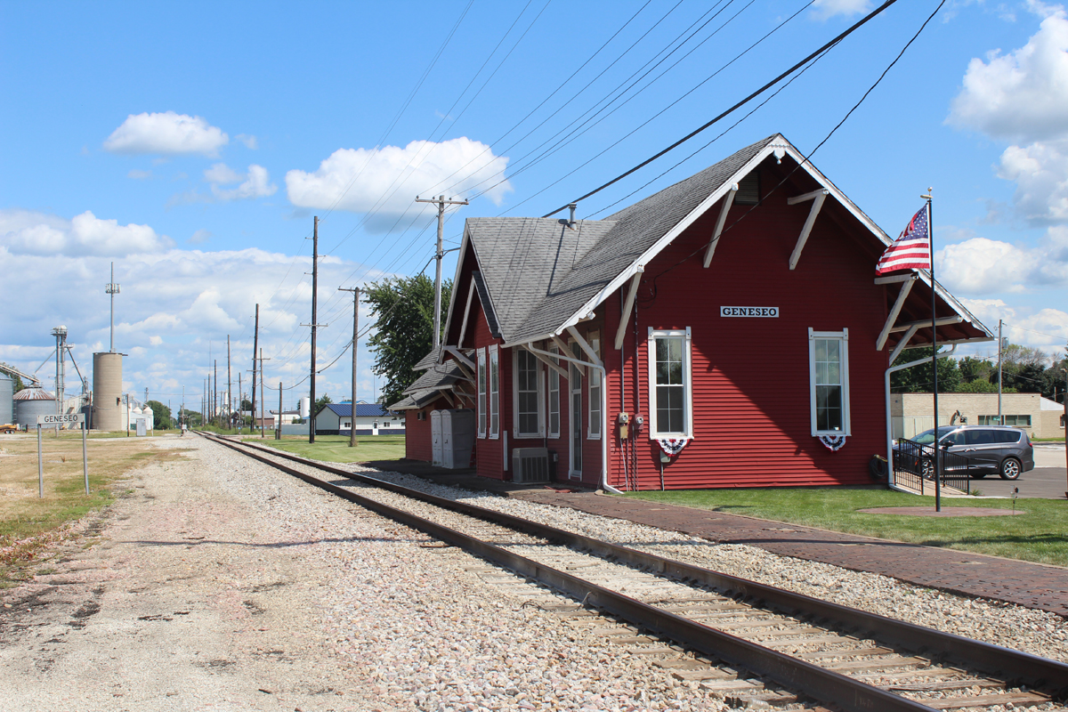 Red wooden railroad station next to single track