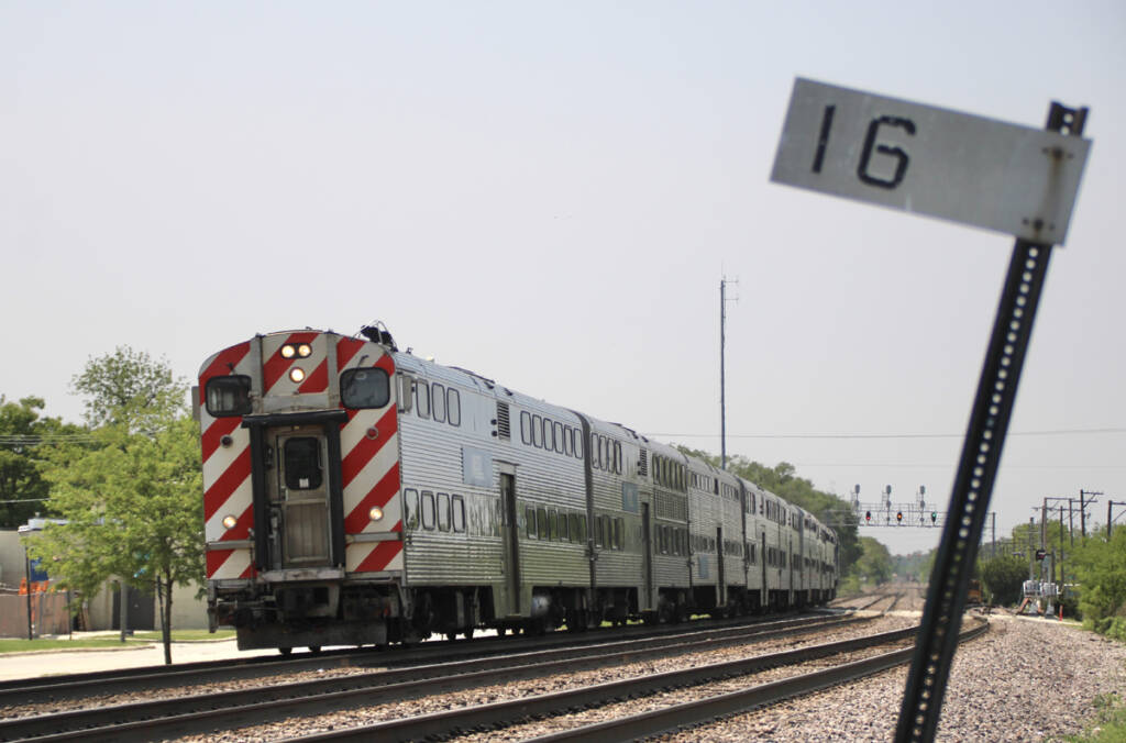 Commuter train led by cab car passes milepost sign