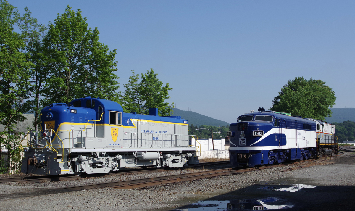 Blue and gray Alco road switcher next to blue and white PA locomotive