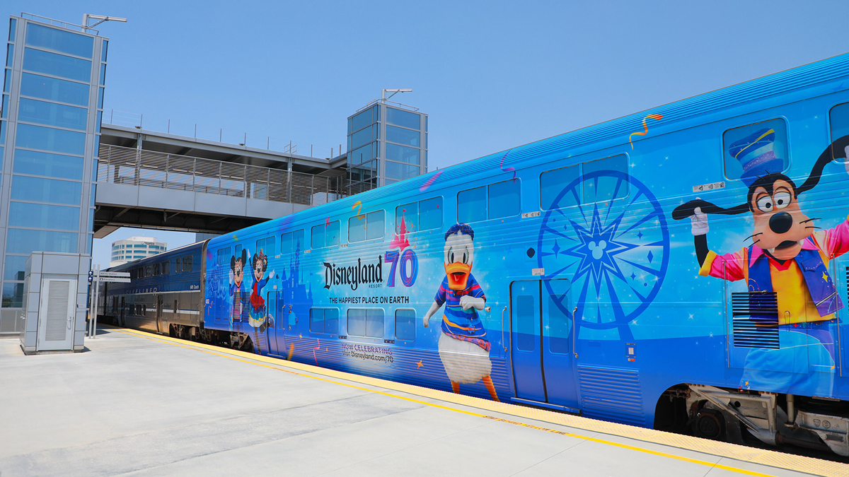 Bilevel passenger car with blue wrap celebrating Disneyland.
