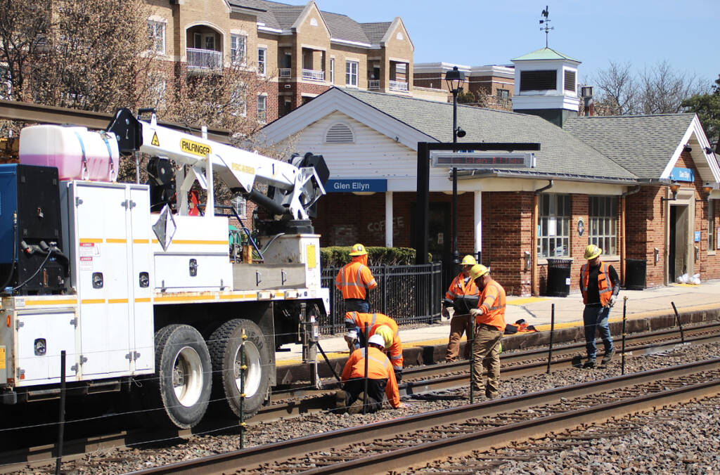 Maintenance-of-way employees working on track in front of station