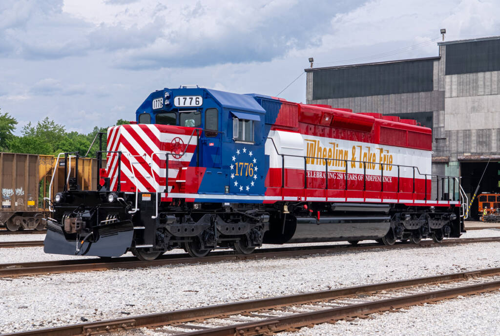 Red, white, and blue locomotive outside shop building