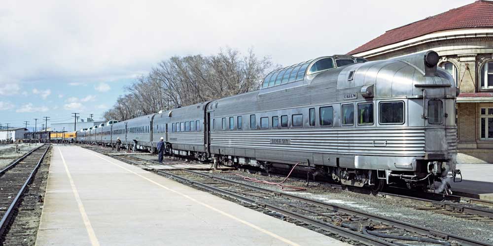 Stainless steel passenger train with dome cars at station