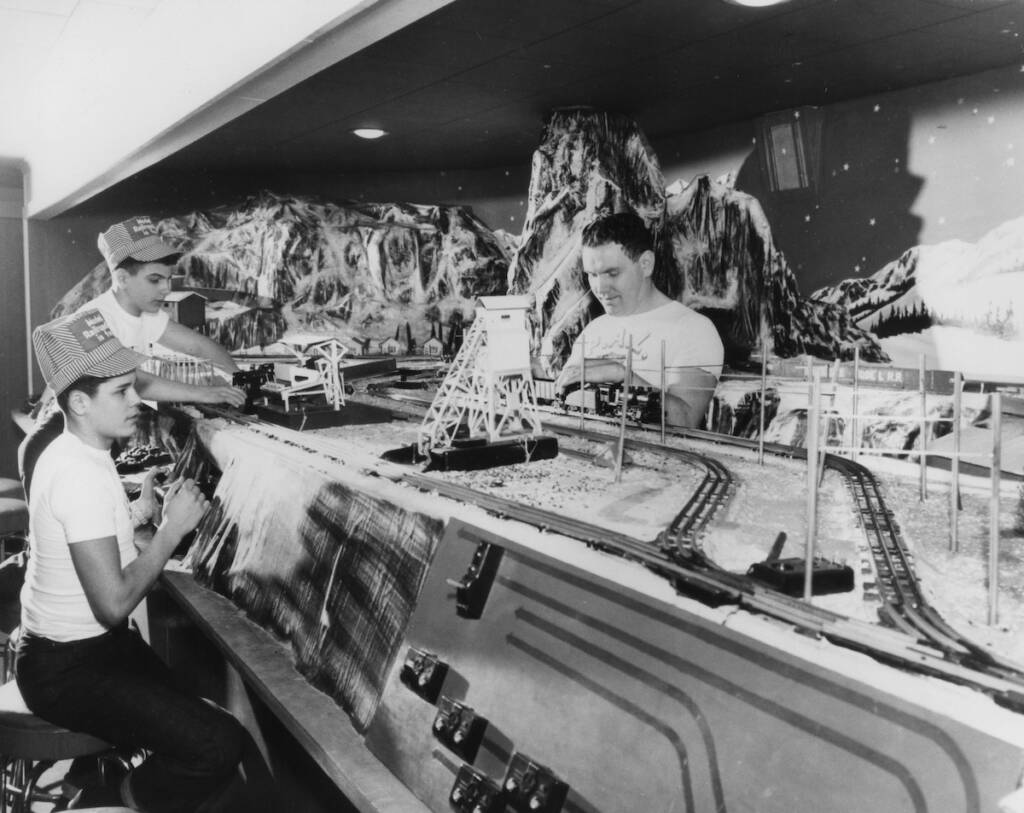 black and white photo of kids next to a train layout