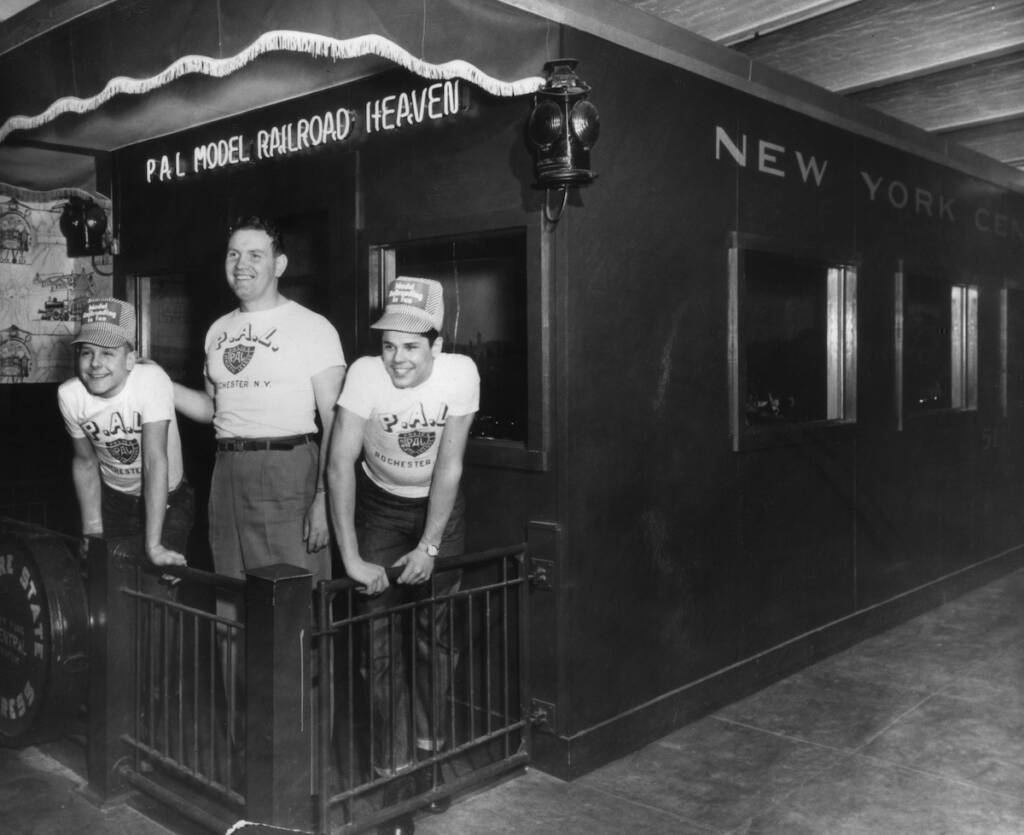  black and white photo of three boys standing on observation car
