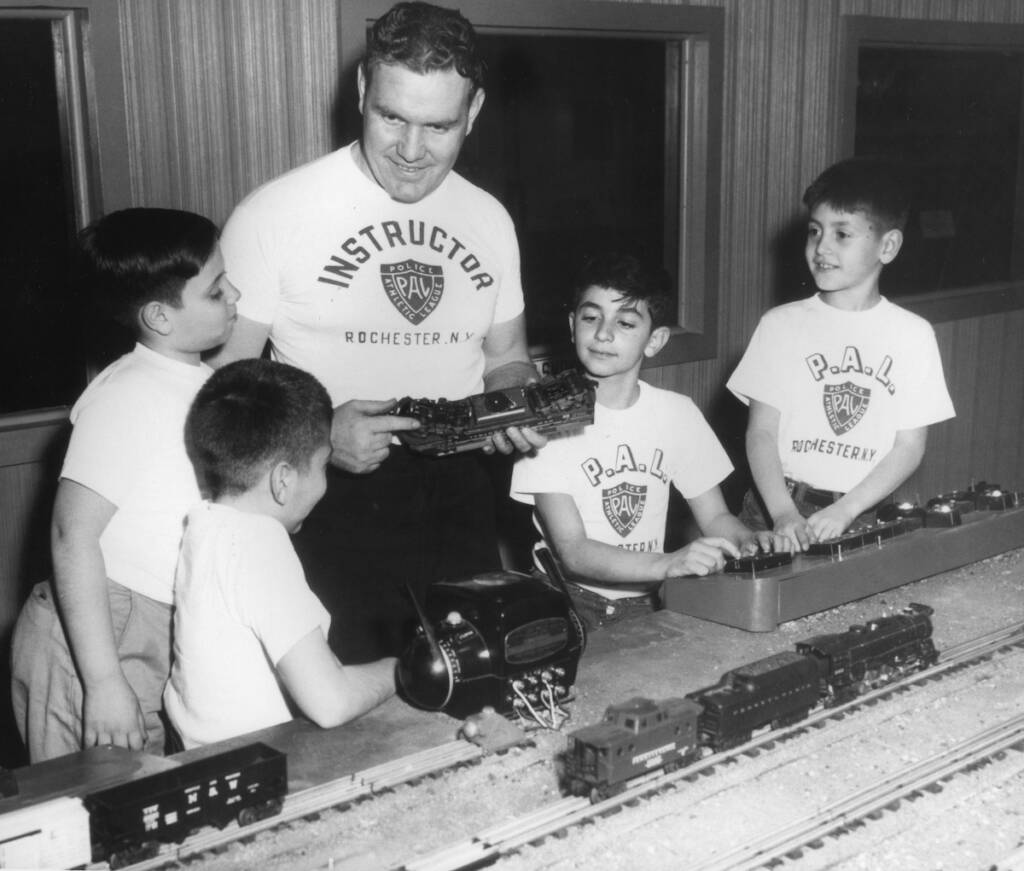 black and white photo of man and four boys next to model train layout