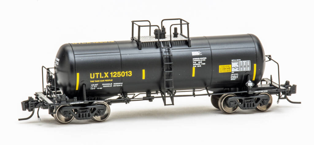 Color photo of N scale tank car painted black with yellow graphics on white background
