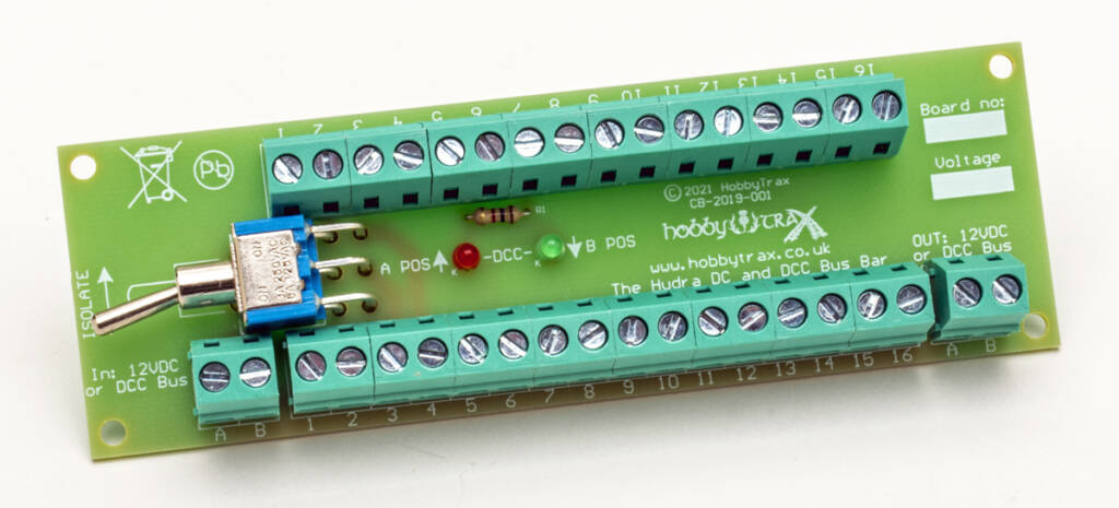 Color photo of green printed-circuit board with screw terminals, switch, light-emitting diodes, and white printing on white background