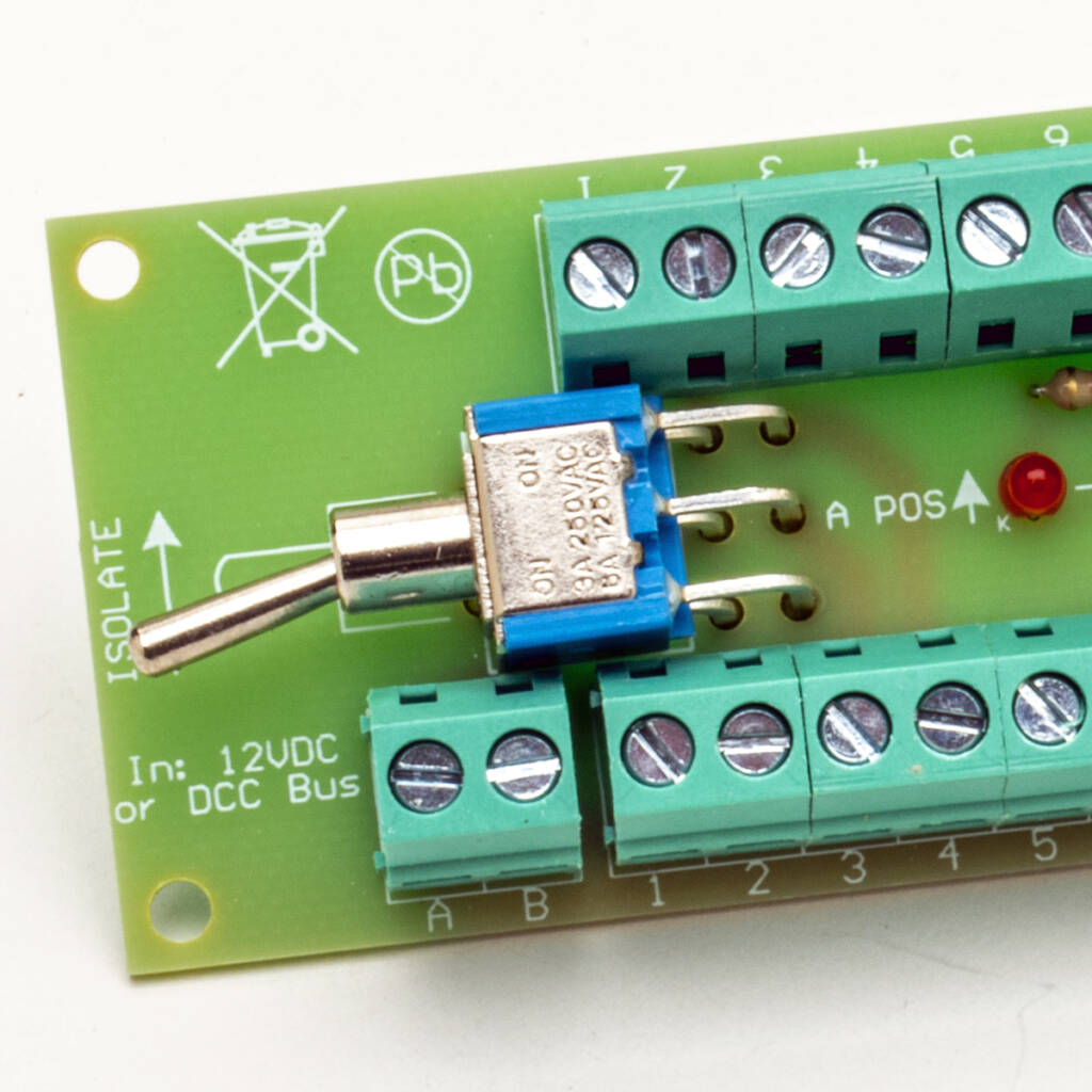 Color photo of green printed-circuit board with screw terminals, switch, light-emitting diodes, and white printing on white background
