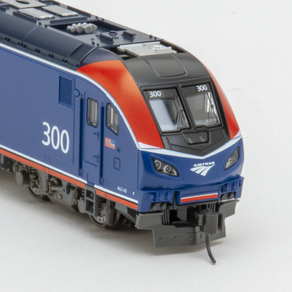 Color photo showing front of modern N scale diesel in red, white, blue, and silver paint on white background