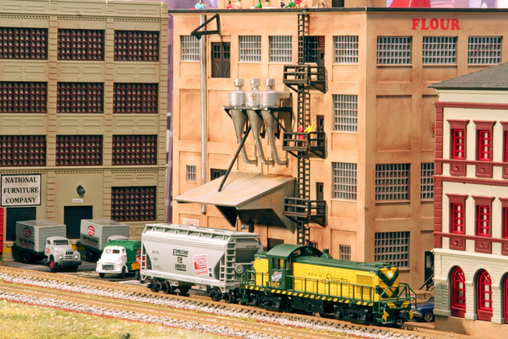 A diesel locomotive in a green and yellow paint scheme witches in an urban industrial setting