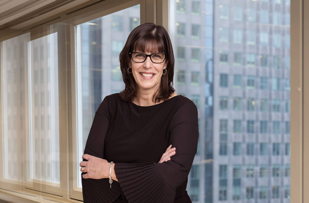 Woman standing in front of window with office building in background