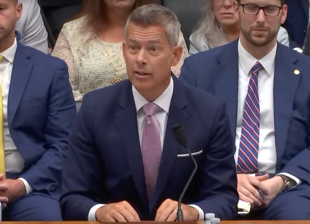 Man in suit speaking from table