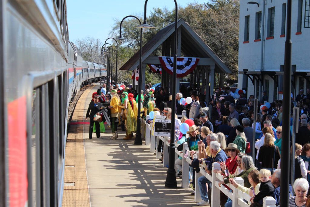 Crowd of people greeting passenger train in view from onboard train