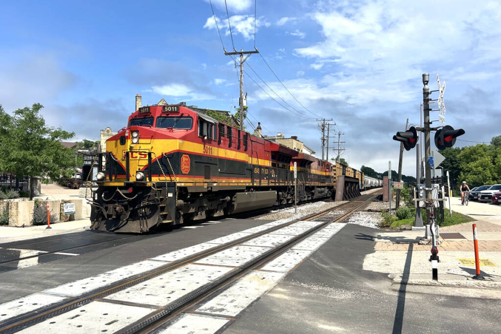 Train with red, yellow, and black locomotives at grade crossing