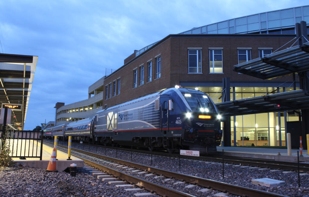 Regional passenger train departs station in evening