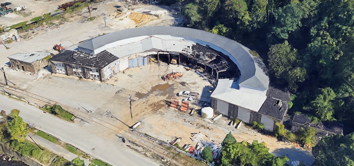 Aerial image of semicircular roundhouse with roof damage in one section